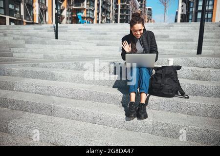 Lächelnde Frau mit einem Laptop auf der Betontreppe Stockfoto