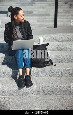 Schöne nachdenkliche Frau mit Eckreihen auf der Betontreppe sitzen Stockfoto