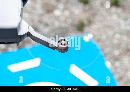 Nahaufnahme der rotierenden Kunststoffpropeller der Drohne mit bürstenlosen Motoren vor dem Hintergrund eines blauen Landeplatts. Stockfoto