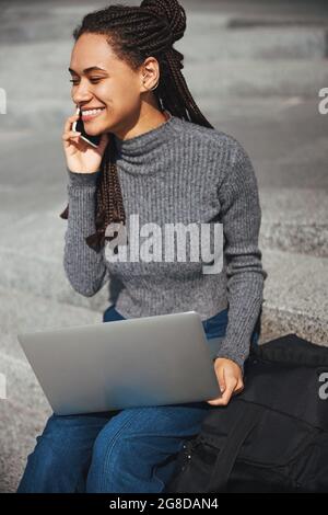 Fröhliche afroamerikanische Frau im Gespräch auf ihrem Smartphone Stockfoto