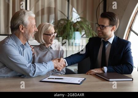 Glückliche ältere Ehepaare schüttelten sich die Hände mit dem makler Stockfoto