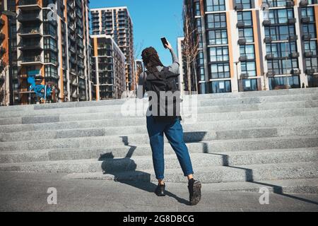 Afroamerikanische Touristin, die sich gegen die Hochhäuser fotografiert Stockfoto