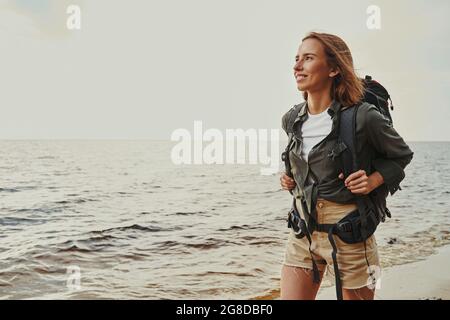Fröhlicher Reisender wandert in der Nähe einer Küste Stockfoto