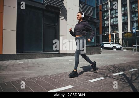 Fröhliches Joggen in kabellosen Kopfhörern, die zur Musik laufen Stockfoto
