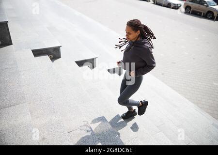 Fokussierter junger Läufer mit den Cornrows beim Joggen oben Stockfoto