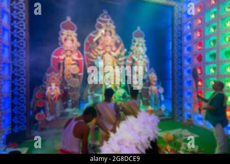 Verschwommenes Bild von hinduistischen bengalischen Priestern, die die Göttin Durga mit Spiegel verehren, Durga aarti im Inneren dekoriertes Durga Puja-Pandal, während des Durga Puja-Festes Stockfoto