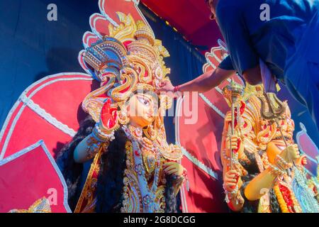 Howrah, Westbengalen, Indien - 5. Oktober 2019 : Hindu-bengalischer Priester, der Zinnoberrot auf die Stirn des Idols der Göttin Laxmi legt, bevor er sie anbetet. D Stockfoto