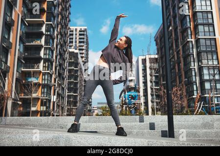 Fröhliche sportliche Frau, die eine seitliche Biegeübung macht Stockfoto