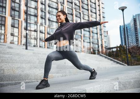 Fröhliche Sportlerin mit Eckreihenübungen auf der Betontreppe Stockfoto