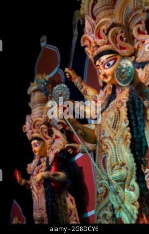 Verschwommenes Bild von Durga und Laxmi Idol bei dekorierten Durga Puja Pandal, Durga Puja Festival in der Nacht. Aufgenommen unter farbigem Licht in Howrah, Westbengalen, I Stockfoto