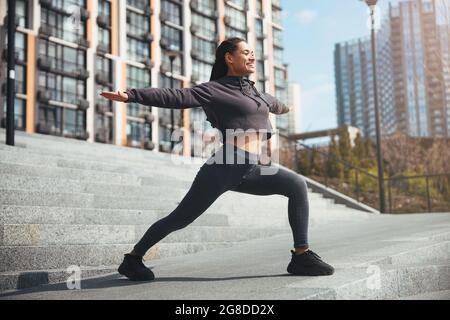 Fröhliche sportliche Frau, die im Freien eine Aufwärmübung durchführt Stockfoto