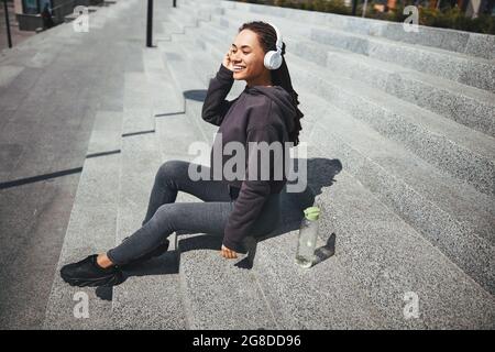 Fröhliche hübsche Dame in kabellosen Kopfhörern, die ihre Lieblingsmusik genießt Stockfoto