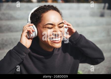 Fröhliche Dame, die ihre Musik mit geschlossenen Augen genießt Stockfoto