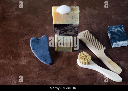 Das Konzept der Naturkosmetik für die Hautpflege - Seife, Gouache, Bürste und Kamm für Haare auf braunem Hintergrund Stockfoto
