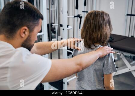 Masseur behandelt Mädchen in medizinischen Reha-Zentrum Rückansicht. Chiropraktiker überprüft Wirbelsäule, Hals Stockfoto