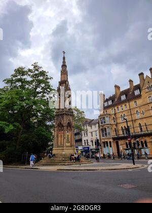 Touristen und Studenten sitzen und entspannen sich auf den Stufen des Martyrs' Memorial, einem Steindenkmal an der Kreuzung von St Giles', Magdalen Street und Beaumont Street, westlich des Balliol College, Oxford, England. Es erinnert an die Oxford Martyrs aus dem 16. Jahrhundert. Das von George Gilbert Scott entworfene Denkmal wurde 1843 nach zweijähriger Arbeit fertiggestellt und ersetzt „ein malerisches, aber totterndes altes Haus“. Vereinigtes Königreich. Stockfoto