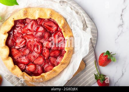 Frische hausgemachte Galette mit Erdbeeren auf weißem Marmorboden. Draufsicht. Nahaufnahme. Stockfoto