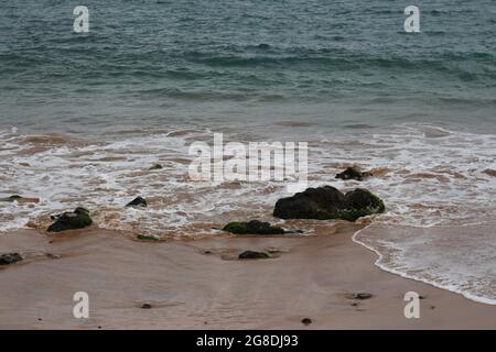 Kleine Wellen Rollen auf einen hellbraunen Sandstrand mit vulkanischem Gestein an der Maalaea Bay in Kihei, Maui, Hawaii, USA Stockfoto