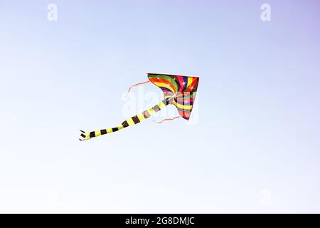 Ein farbenfroher Drachen fliegt im Wind hoch am Himmel. Unterhaltung für Kinder, Spaß im Freien für Kinder im Sommer. Ein Konzept der Freiheit, j Stockfoto