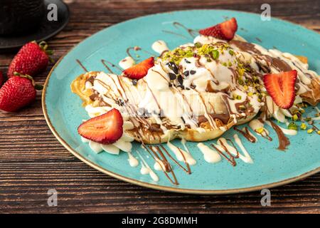 Herzwaffel mit Banane und Erdbeere mit Gummy Candy und Eis darauf. Stockfoto