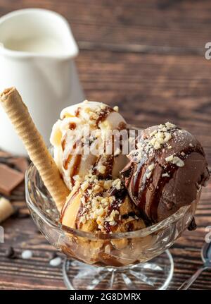 Schokolade, Rahm und Karamell-Roma-Eis in einer Glasschüssel mit Haselnuss- und Schokoladensauce darüber gegossen. Stockfoto