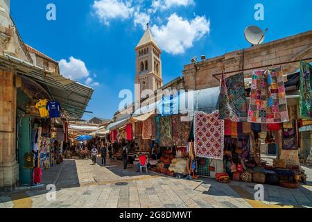 Blick auf die schmale Straße mit traditionellen Souvenir- und Teppichgeschäften in Muristan - christliches Viertel in der Altstadt von Jerusalem, Israel. Stockfoto