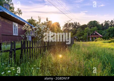 Schönes, traditionelles, polnisches Dorf bei Sonnenuntergang. Alte, hölzerne Gebäude neben grüner, frischer Wiese. Idyllischer Blick auf die Landschaft. Krasnobród, Roztocz Stockfoto