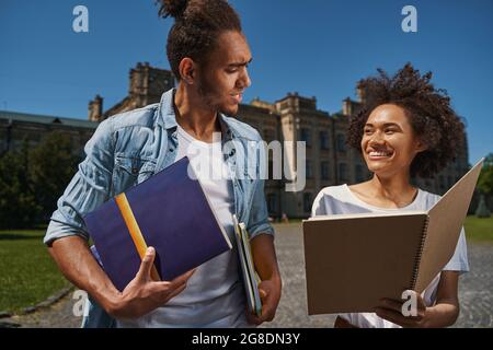 Freundliche Studenten teilen ihre Arbeitsbücher nach dem Vortrag Stockfoto