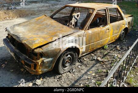 Verbrannte Autolimousine nach Straßenunruhen. Weitwinkelaufnahme Stockfoto