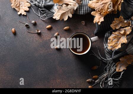 Trendiger gesunder Eichelkaffee ohne Koffein auf braunem Tisch mit Herbsteichenblättern und gemütlichem Schal. Blick von oben. Platz für Text. Ersatzkaffee. Stockfoto