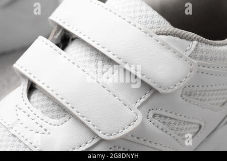 Foto von weißen Kinder Sneakers. Makrofotografie von Sport-Sneakers aus Leder und Stoff mit Klettverschluss, Draufsicht, monochrom Stockfoto