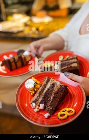 Ein Kellner servierte zwei Stück Kuchen auf Tellern. Er hält zwei Teller mit einer Hand Stockfoto