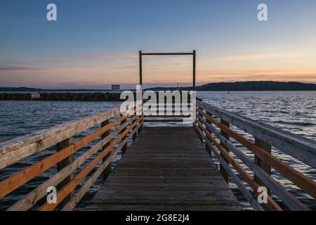 Hölzerner Pier, Der Sich Während Des Sonnenuntergangs Über Dem Wasser Erstreckt Stockfoto