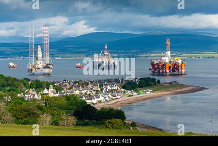 Blick auf das Dorf Cromarty und alte und gasbetriebene Plattformen und Bohrinseln, die in Nigg Bay auf der Black Isle auf Cromarty Firth, Ross und Cromarty, Schottland, festgemacht sind, Stockfoto