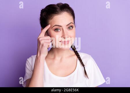 Porträt der freundlichen zufriedenen Person Finger auf Tempel Lächeln Blick Kamera isoliert auf lila Hintergrund Stockfoto