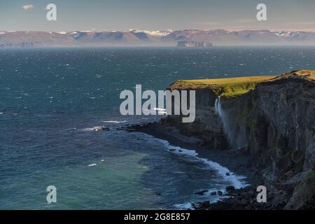 Der Wasserfall fällt über die Klippe und wird vom Wind weggeblasen, im Hintergrund Saga Island Drangey, Skagi Peninsula, Skagafjoerour, Norourland Vestra Stockfoto