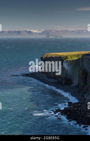 Der Wasserfall fällt über die Klippe und wird vom Wind weggeblasen, im Hintergrund Saga Island Drangey, Skagi Peninsula, Skagafjoerour, Norourland Vestra Stockfoto