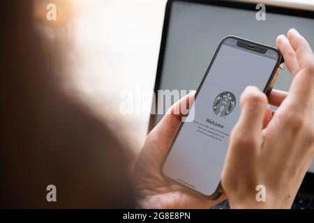 Chiang Mai, Thailand : JULY 17 2021 : Asiatische Frau, die Starbucks Anwendung für die Zahlung auf dem iPhone Bildschirm im Starbucks Café verwendet. Stockfoto