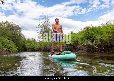 Abenteuerliche hispanische Erwachsene Athletic man Paddle Boarding Stockfoto