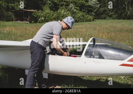 Der Segelflieger bereitet sich auf den Flug mit motorlosen Festflügelflugzeugen vor. Kleine Luftfahrt Extremsport Freizeitbeschäftigung. Mann in der Nähe des Flugzeugs Stockfoto