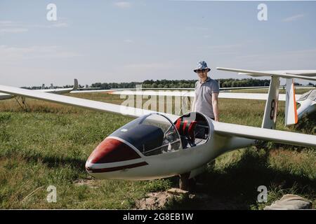 Der Segelflieger bereitet sich auf den Flug mit motorlosen Festflügelflugzeugen vor. Kleine Luftfahrt Extremsport Freizeitbeschäftigung. Mann in der Nähe des Flugzeugs Stockfoto