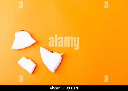 Happy Coconuts Tageskonzept, frische Kokosnuss Gruppe Stücke Scheiben, Studio Shot isoliert auf orangenen Hintergrund Stockfoto