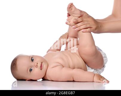 Kleinkind Baby Mädchen Kind in Windel liegt auf ihrem Rücken macht Übungen, Knie mit erwachsenen Trainer, Mutter beugen. Seitenansicht Stockfoto