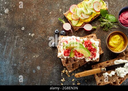 Von oben von verschiedenen Knäckebrot Toasts mit reifen Gemüse serviert auf dunklen Tisch im Studio Stockfoto