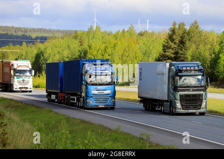 Der Sattelschlepper Volvo FH überholt den blauen DAF XF mit einer Ladung von zwei Seecontainern, die im Autobahnverkehr bergauf fahren. Salo, Finnland. 28.Mai 2021 Stockfoto