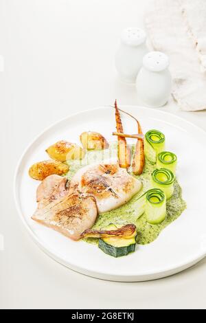 Gegrillter Tintenfisch mit Gemüse. Tintenfisch mit Babykartoffeln, Zucchini, Gemüse der Saison und Kräutersauce. Mediterrane Küche. Lecker und gesund Stockfoto