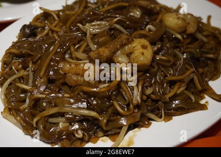 Char Kway Teow ist ein chinesisch inspiriertes Reisnudel-Gericht aus Südostasien, das mit einem Rührbraten zubereitet wird. Stockfoto