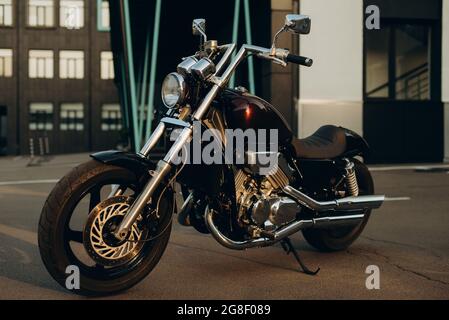 Ein Motorrad auf einem Parkplatz im warmen Licht eines Sonnenuntergangs. Stylische Custom Chopper Motobike mit Chrom-Details. Weicher, selektiver Fokus. Stockfoto