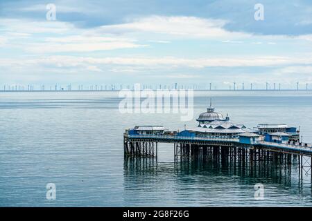 LLANDUDNO, WALES - 04. JULI 2021: Blick auf den Llandudno Pier und einen 576-Megawatt-Windpark Gwynt-y-Mor. Stockfoto