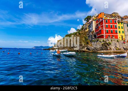 CINQUE TERRE, ITALIEN - 18. Juli 2019: Klassischer Blick auf Manarola - Bunte Häuser in einer dramatischen Felsformation am Meer mit einem natürlichen Fischfang Stockfoto